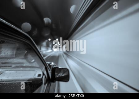 Aufnahme eines Autos in Bewegung und Geschwindigkeit, das in einem Schwarzweißfoto von tunnelб fährt Stockfoto
