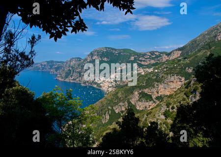 Wandern an der Amalfiküste. Die Annäherung nach Positano in der Entfernung vom Walk of the Gods. Tyrrhenische See, Mittelmeer, Italien. Amalfiküste. Halbinsel Sorrent. Sentiero degli Dei. Boote in der Bucht vor Positano. Stockfoto