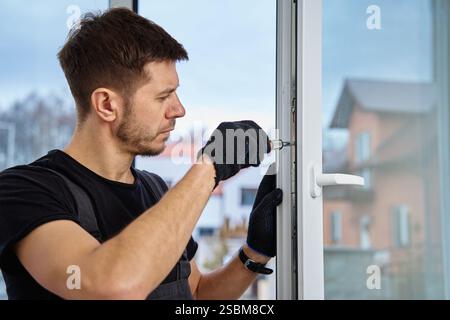 Professioneller Techniker, der weiße pvc-Fenster in einem modernen Gebäude einstellt. Bauarbeiter, der Kunststofffenster in einem neuen Zuhause installiert. Reparaturkonzept an Stockfoto