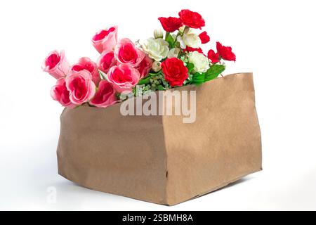 Ein atemberaubender Blumenstrauß aus rosa, roten und weißen künstlichen Rosen mit üppigem Laub in einer Papiertüte auf weißem Hintergrund, perfekt für Dekoration und Geschenke Stockfoto