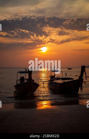 Wunderschöne Aussicht auf Langboot-Boote in Silhouette, Meer und atemberaubendem orangefarbenen Himmel bei Sonnenuntergang am Railay West Beach in Railay, Krabi, Thailand. Stockfoto
