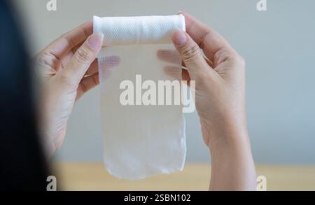 Nahaufnahme von weiblichen Händen, die einen weißen medizinischen Baumwollgaze-Verband halten. Selektiver Fokus, Rückansicht. Stockfoto