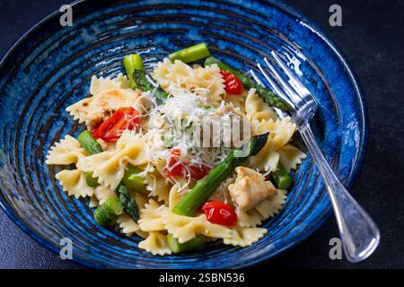 Farfalle Pasta mit grünem Spargel, Kirschtomaten und Huhn Stockfoto