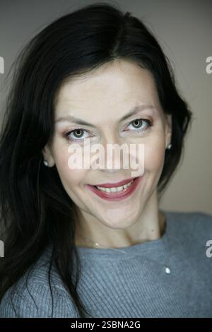 Lächelnde brünette Frau im mittleren Alter von 51 Jahren im roten langen Seidenrock und indischen Ohrringen, die am Strand in der Nähe des Meeres posiert Stockfoto