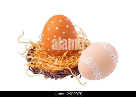 Ostereier mit weißem Ornament in einem Nest mit Stroh isoliert auf weißem Hintergrund Stockfoto