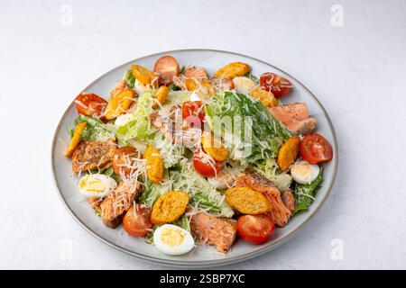 Caesar-Salat mit Forelle (Lachs), Kirschtomaten, Croutons, Parmesankäse, Wachteleiern und Römersalat. Traditionelles amerikanisches Gericht. Nahaufnahme, Auswahl Stockfoto
