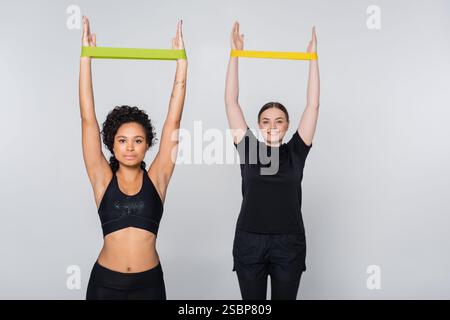 Zwei Frauen zeigen Stärke durch Übungen mit Widerstandsband in einer hellen Umgebung. Stockfoto