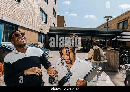 Glückliche männliche und weibliche Freunde, die auf dem College-Campus lachen Stockfoto