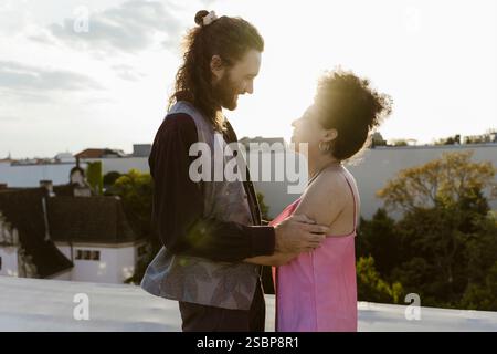 Seitenansicht eines frisch verheirateten, multirassischen Paares, das sich auf dem Dach ansieht Stockfoto