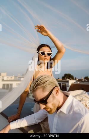 Junge Frau und Mann sitzen unter Schleier auf dem Dach Stockfoto