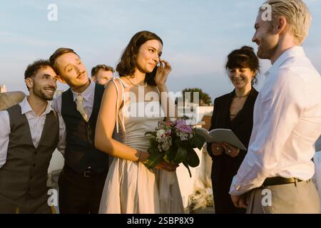 Gäste und eine Priesterin mit verheirateten Paaren, die während der Zeremonie Gelübde austauschen Stockfoto