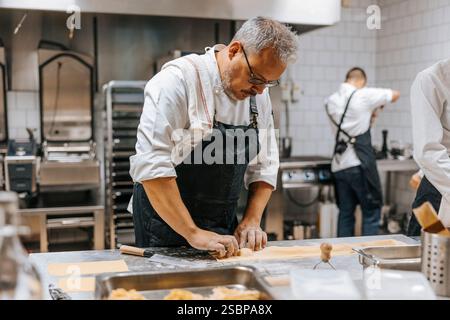 Reifer männlicher Koch, der Knödel an der Küchentheke im Restaurant macht Stockfoto