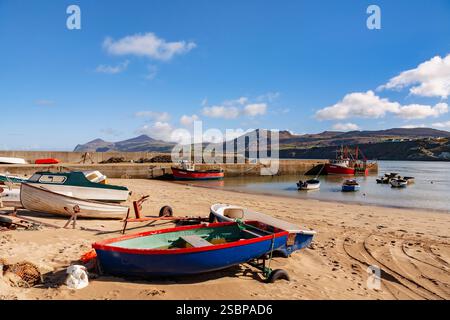 Boote am Sandstrand mit festgefahrenem Trawler am Steg am kleinen Fischerhafen Porth Nefyn und Blick über die Bucht auf der Halbinsel Llyn. Nefyn, Gwynedd, Wales, Großbritannien Stockfoto
