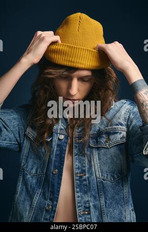 Junger Mann in trendiger Jeansjacke und gelber Beanie sorgt für ein schickes modisches Statement. Stockfoto