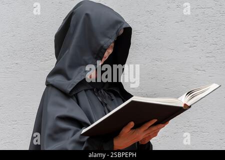 Eine reife Dame im Nonnenkleid hält ein altes Buch Stockfoto