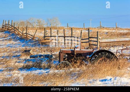 Der Traktor sitzt auf einem Feld im Schnee. Der Traktor ist alt und rostig Stockfoto