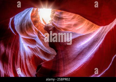 Ein rot-blauer Canyon, durch den die Sonne scheint. Der Canyon ist sehr schmal und die Sonne scheint durch den Gipfel Stockfoto