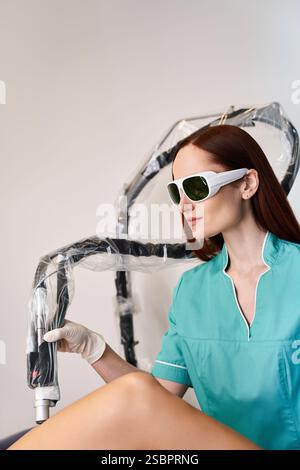 Eine junge, schöne Frau, die eine Schutzbrille trägt, entspannt sich, bevor sie sich einer Laser-Haarentfernung unterzieht. Stockfoto