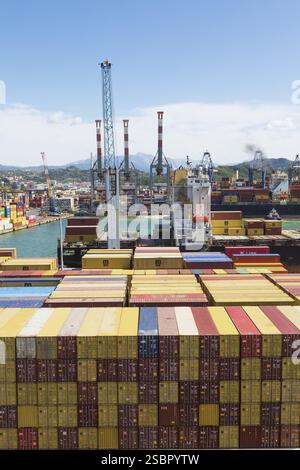 Hochwinkelansicht der gestapelten rechteckigen Transportbehälter aus Metall und Portalkräne am Dock im Frachthafen La Spezia, Italien, Europa Stockfoto
