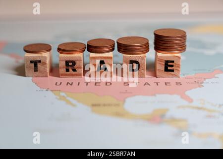 Holzblöcke, die DEN HANDEL beschreiben, sind in einem aufsteigenden Graphmuster angeordnet, jedes mit einem Stapel Münzen gekrönt, über einer Karte der Vereinigten Staaten. Hohe Qualität Stockfoto