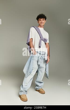 Junger Mann posiert selbstbewusst in trendigen Baggy-Hosen und einem lässigen Lagenoberteil. Stockfoto