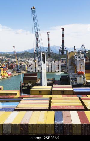 Hochwinkelansicht der gestapelten rechteckigen Transportbehälter aus Metall und Portalkräne am Dock im Frachthafen La Spezia, Italien, Europa Stockfoto