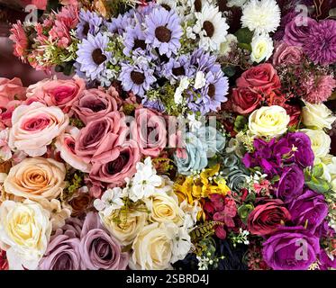 Schöne Rosenblumen Arrangement in vielen Farben, von rot, kastanienbraun, lila, rosa, auf blaue Farbe. Serie von Rosenblumenstrauß mit Gänseblümchenblümchen Stockfoto