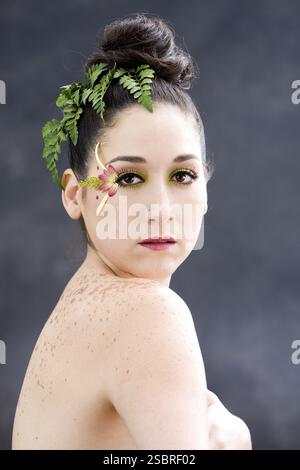 Schönes brünettes Gesicht mit rosafarbenem, gelbem Augenblüten-Make-up, isoliert auf Grau, New York, USA, Nordamerika Stockfoto