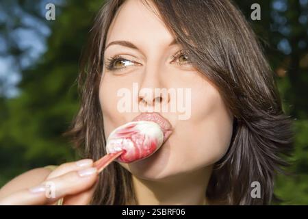 Junge Brünette, die Eis im Park isst Stockfoto