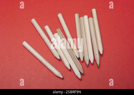 Buntstifte auf rotem Hintergrund. Viele Buntstifte Stockfoto