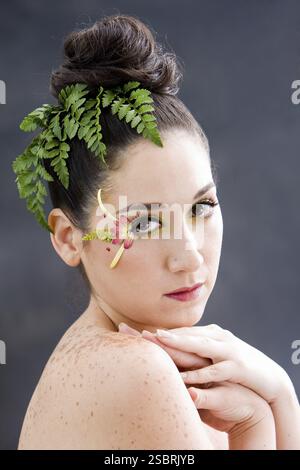 Schönes brünettes Gesicht mit rosafarbenem, gelbem Augenblüten-Make-up, isoliert auf Grau, New York, USA, Nordamerika Stockfoto