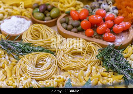 Ein Tisch voller Speisen, darunter Nudeln, Oliven, Tomaten und Wachteleier. Der Tisch ist für eine Mahlzeit gedeckt und das Essen sieht köstlich aus Stockfoto