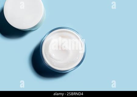 Öffnen Sie den Kosmetikbecher auf blauem Hintergrund, Draufsicht, Kopierraum. Gel-Schönheitsprodukt für die Anti-Akne-Gesichtspflege, tägliche Routine. Geöffnete Kollagenkosmeti Stockfoto