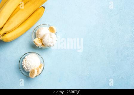 Eislöffel und Bananenscheiben in Schüsseln auf blauem Hintergrund, Draufsicht, Kopierraum. Gesundes rohes veganes Bananeneis (Nicecream), hausgemachte Bio Stockfoto