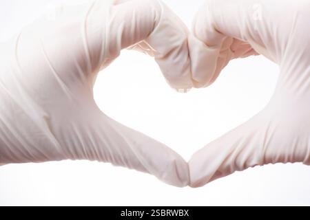 Hände in Latexhandschuhe zeigen Form des Herzens auf weißem Hintergrund Stockfoto