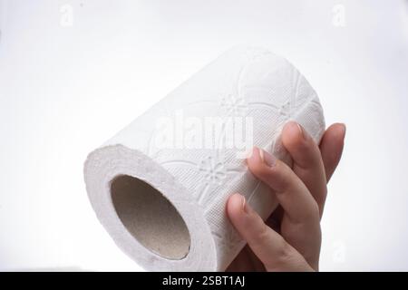 Eine weibliche Hand nimmt eine Rolle weißes Toilettenpapier in die Hand Stockfoto