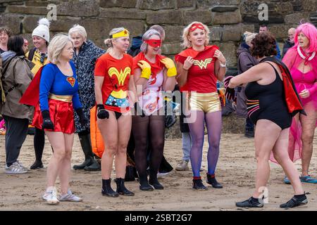 Teilnehmer treffen sich am Strand von Towan und bereiten sich auf die jährliche Veranstaltung „Superheld in the Cold“ vor, um Mittel für Cancer Research UK zu sammeln. Stockfoto