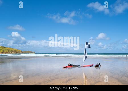 Zwei müde Surfer, die eine Pause vom Surfen machen und sich neben ihren Surfbrettern am Towan Beach in Newquay in Cornwall in Großbritannien niederlegen. Stockfoto