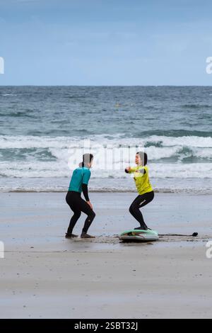 Ein Surflehrer von der Escape Surfing School, der eine Surfstunde mit einer Lernerin am Towan Beach in Newquay Cornwall, Großbritannien, abhält. Stockfoto