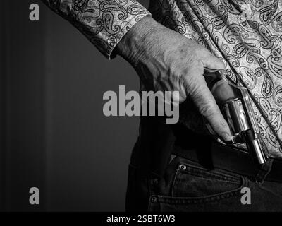 Ein Mann hält einen kleinen Nasenrevolver in der rechten Hand. Film Noir Schwarz-weiß-Stil. Stockfoto