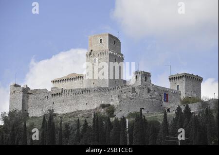 Schloss Rocca Maggiore in Assisi, Umbrien, Italien, Europa, große mittelalterliche Burg auf einem Hügel umgeben von Zypressen. Beeindruckend gegen einen teilweise bewölkten bl Stockfoto