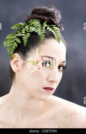 Schönes brünettes Gesicht mit rosafarbenem, gelbem Augenblüten-Make-up, isoliert auf Grau, New York, USA, Nordamerika Stockfoto