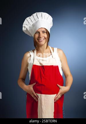 Ein Brötchen im Ofen. Glückliche schwangere Frau kocht Stockfoto