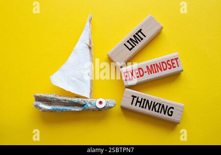 Begrenzen Sie das Denksymbol für feste Denkweisen. Konzeptworte beschränken das Denken auf Holzblöcke. Schöner gelber Hintergrund mit Boot. Business-Konz Stockfoto