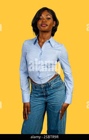 Studio-Porträt einer stilvollen jungen Frau, die vor einem leuchtend gelben Hintergrund Selbstvertrauen ausstrahlt Stockfoto