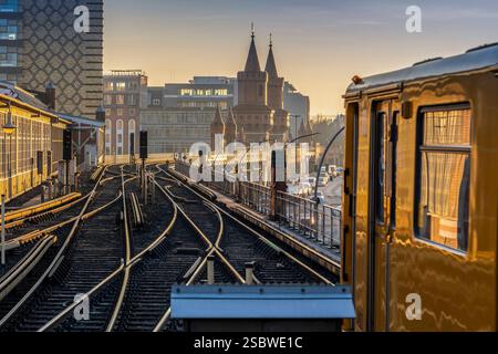 Eine U-Bahn am Bahnhof Warschauer Straße. Hier verkehren U-Bahnen der Linie U1 und U3. Im Hintergrund die Türme der Oberbaumbrücke über die Spree. *** U-Bahn am Bahnhof Warschauer Straße U-Bahn-Züge der Linien U1 und U3 fahren hier die Türme der Oberbaumbrücke über die Spree im Hintergrund Stockfoto