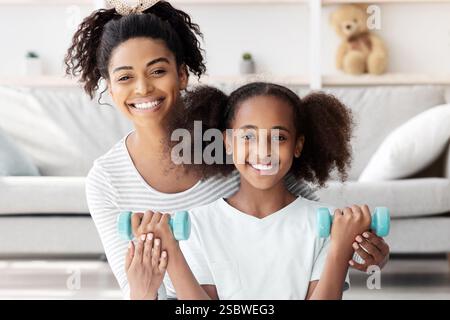 Positive afroamerikanische Mutter und Tochter mit Langhanteln Stockfoto