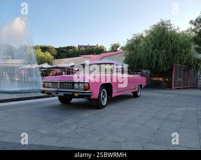 Knallig rosa Oldtimer Chaika neben einem Brunnen in Odesa, Ukraine Stockfoto
