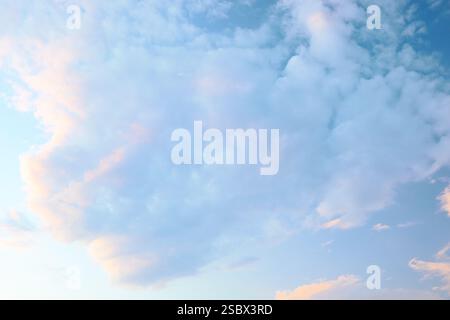 Wunderschöne Wolken reflektieren sanfte Farbtöne am Abendhimmel über einer ruhigen Landschaft während der Sonnenuntergänge. Stockfoto