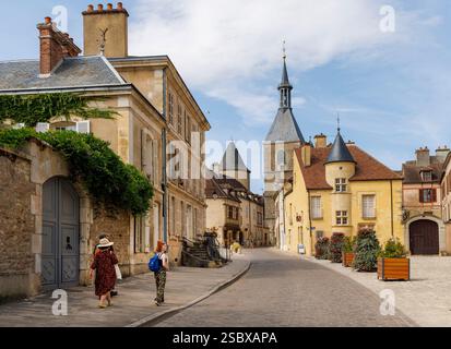 Menschen, die durch ruhige Straßen mit dem Uhrturm in der Ferne laufen, Avallon, Yonne, Burgund, Bourgogne-Franche-Comté, Frankreich Stockfoto